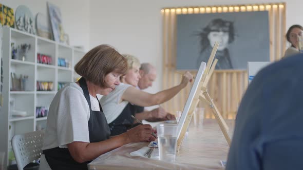 The Teacher Shows a Group of Friends of Retired People in the Elderly at Drawing Courses alt