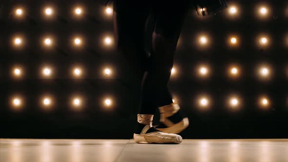 Feet of Ballerina in Pointe Shoes is Dancing Ballet in the Dark Studio