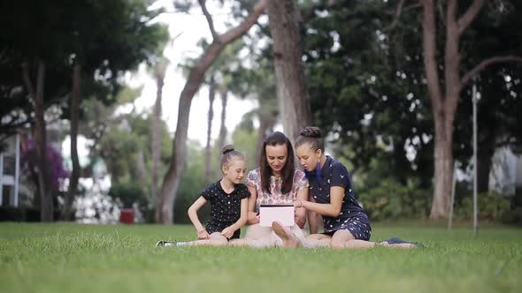 Mother and Daughter on the Grass with Tablet