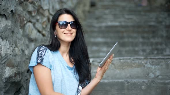 Young Woman Tourist is Reading Interesting Historical Facts on Touch Pad During a Tour in the Old alt