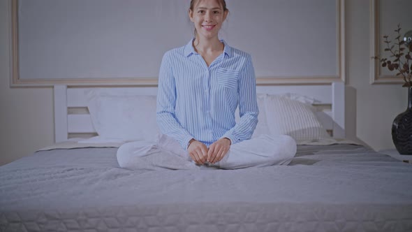Blonde Female Wearing Pajamas Sits in Bedroom