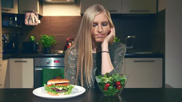 Young Woman Choosing Between Hamburger and Salad. alt