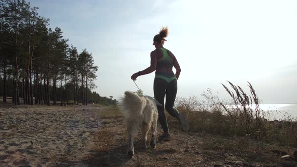 Athletic Woman Running Along Coastline with Dog alt