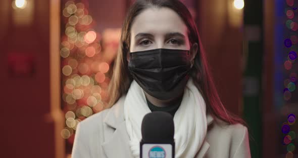 Young woman reporter looking around in surgical mask.