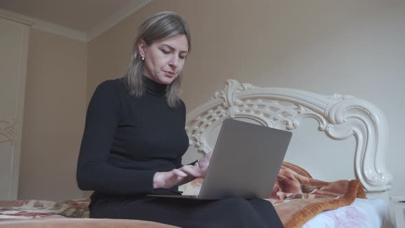 A Woman Sits on Her Bed and Makes Purchases Online Using a Bank Card
