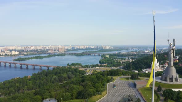 Aerial View of the Ukrainian Flag Waving in the Wind Against the City of Kyiv alt