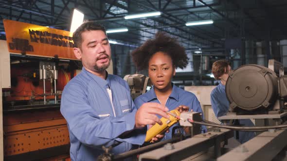 Two professional engineers inspect machines' electric systems at the factory. alt