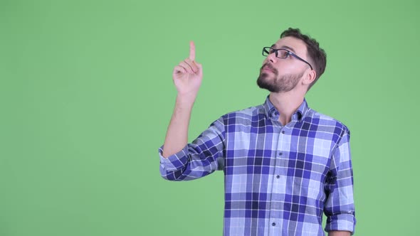 Happy Young Bearded Hipster Man Talking While Pointing Up alt