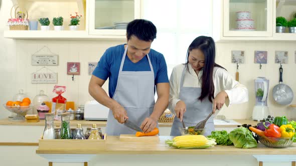 Young Asian Couple are Teasing While Cooking in the Kitchen by pixs4u