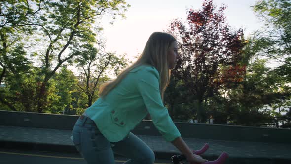 Young Stylish Woman Cyclist Enjoying Fixed Gear Bike Riding Outdoors at Sunrise Near the Sea alt