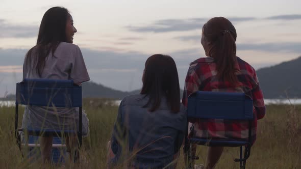 Group of a young teen Asian woman sitting on a chair with friends drinking beer and looking view.