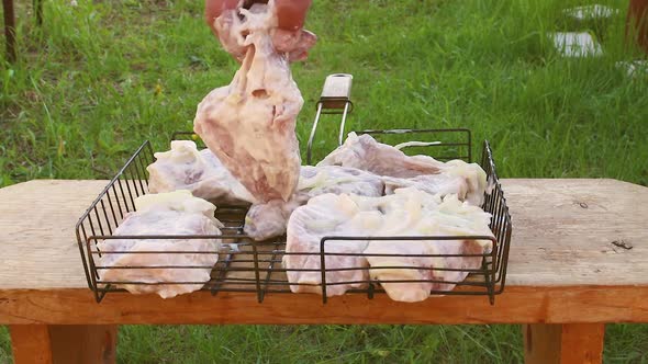 A Man's Hand Lays Out Large Chunks of Barbecue Meat on the Wire Rack alt