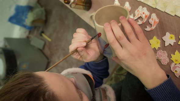 Female Ceramist Paints a Clay Product