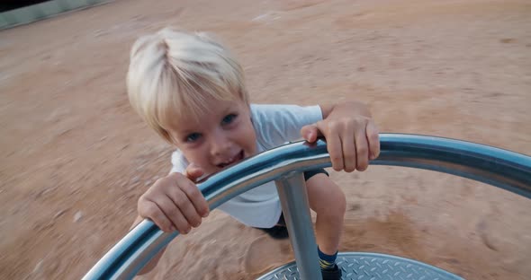 Happy child on playground spinning on carousel swing and laughing on sunset