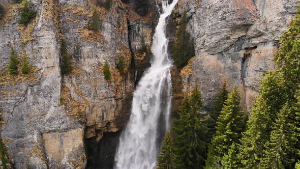 Flying over a green forest around a big waterfall in the mountains. Waterfall Aerial View. alt