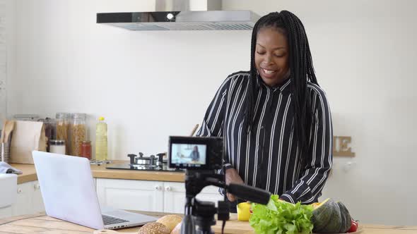 Happy african american woman vlogger broadcasting live video online teaching cooking at home