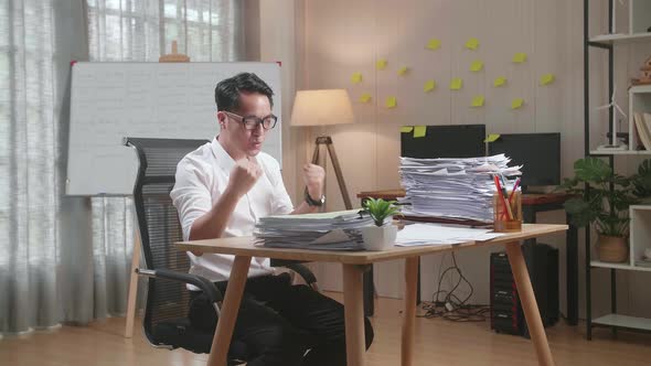 Happy Asian Man Celebrating Finishing Working With Documents At The Office alt