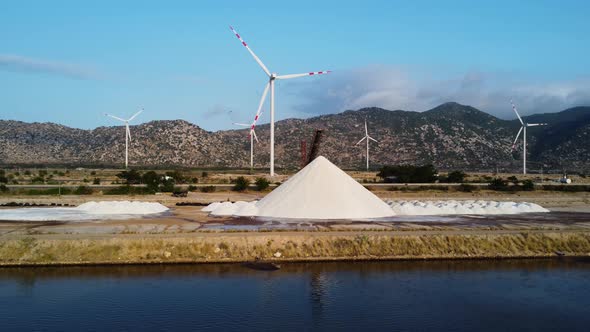 Heap Of Salts At Salt Pan With Wind Turbines In The Distance. - aerial alt