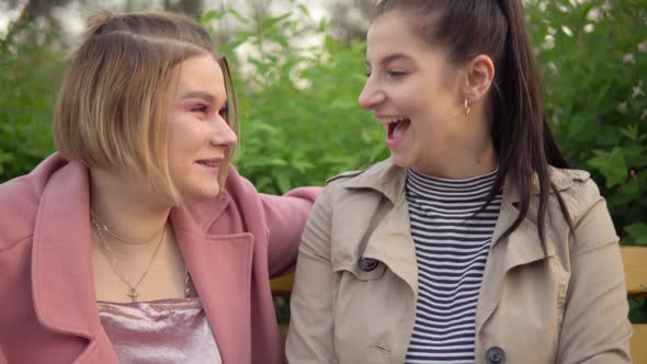 Two Attractive Happy Girls Looking at Phone Screen Laughing Friendship Concept