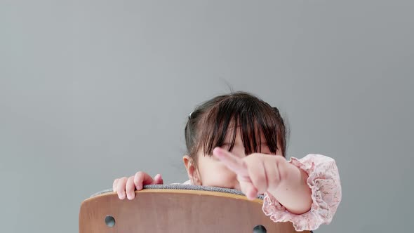 Child playing on the chair at home and looking at camera. Kids happy concept. alt