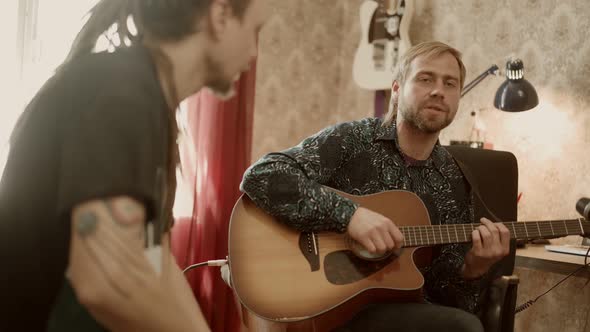 Man Playing Guitar and Singing Near Friend