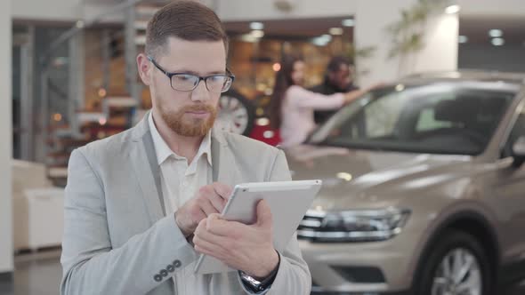 Close-up Portrait of Serious Caucasian Man Checking His Tablet, Looking at Camera and Gesturing Yes alt