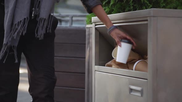 Cropped Image of Stylish Woman in Blue Scarf Throwing Empty Paper Cup to Garbage Can for Paper alt