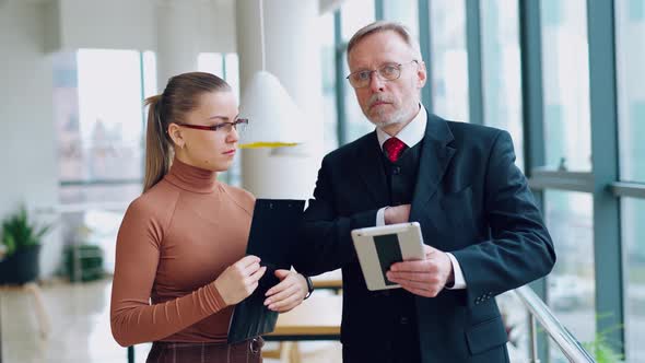 Boss is giving a pen to a woman assistant for signing papers in office alt