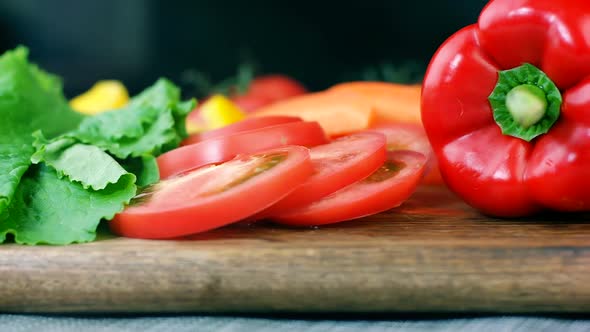 Salad leaves, cutted tomato, bell pepper and carrot on a wooden board