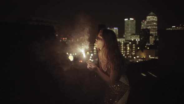 Young adult woman dancing on rooftop with sparkler, celebrating, party, new years eve