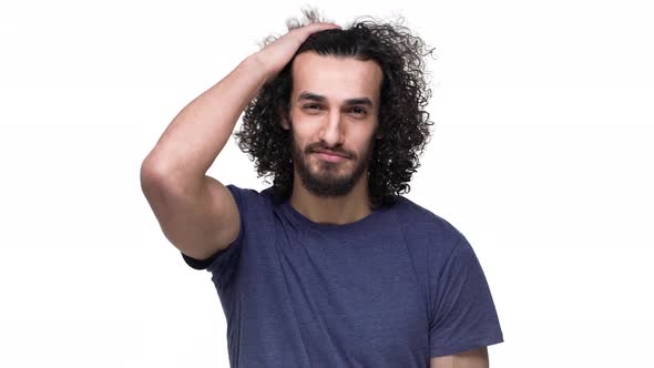 Portrait of Brazilian Guy in Basic Clothing Smiling and Touching His Curly Dark Hair Isolated Over alt