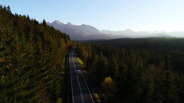 Aerial view of mountain twisted road and luxury SUV car driving to the mountains. Beautiful autumn