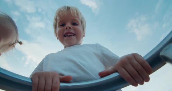 Happy child on playground spinning on carousel swing and laughing on sunset alt