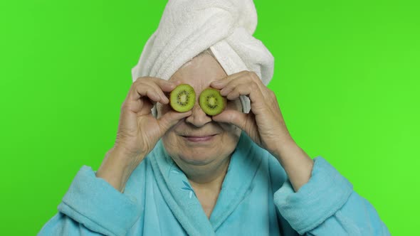 Elderly Grandmother in Bathrobe After Shower. Old Woman with Two Halves of Kiwi alt