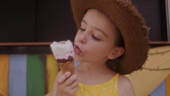 Little Girl in Straw Hat Eating Ice-cream Outdoors Street. Summer Portrait alt