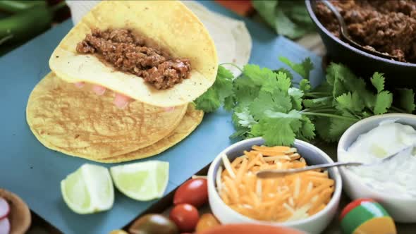 Time-lapse. Serving ground beef tacos with romaine lettuce, diced tomatoes, radishes, and shredded c alt