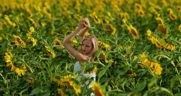 Beautiful Woman Dances in a Field with Sunflowers Raises Her Hands to the Top and Turns alt