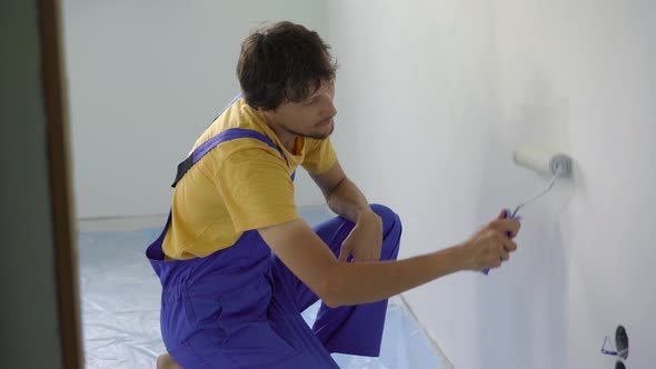 A Man Professional Construction Worker Paint the Wall Using a Roller Painter alt