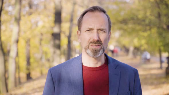 A Middleaged Handsome Caucasian Man Talks to the Camera As He Walks in a Park in Fall