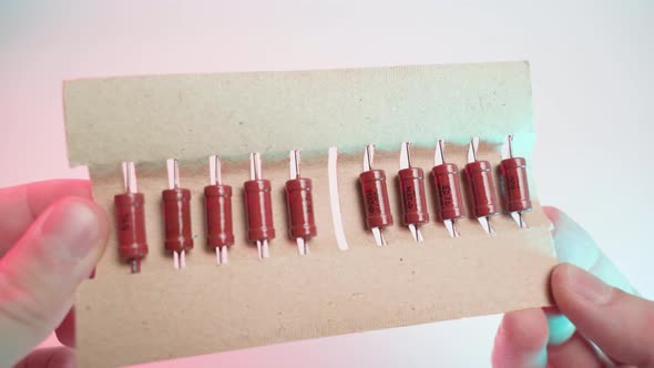 Old Orange Resistors Close Up in a Paper Package in Hands on a White Background Closeup in Colored alt