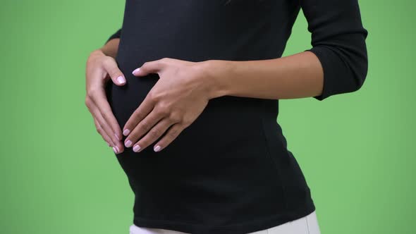 Young Pregnant Woman Showing Hand Heart Gesture To Her Stomach