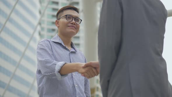 Asian businessman shaking hands with partners have success while standing in the urban city.