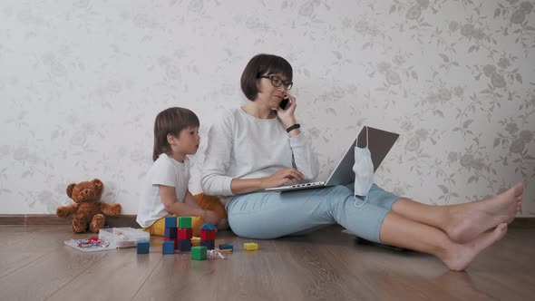 Mom and Son Sit at Home Quarantine Because of Coronavirus COVID19. Mother Remote Works with Laptop
