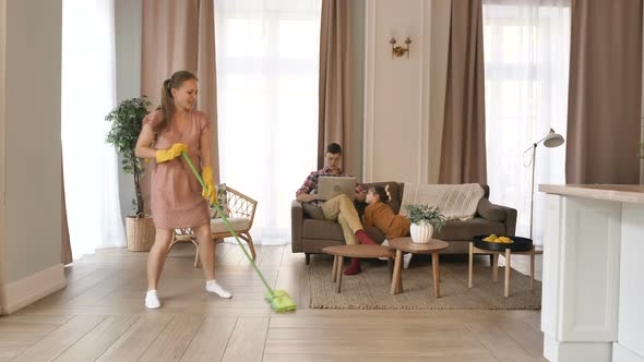 Family Self-isolation at Home During the Coronavirus Pandemic. Husband Works Remotely on a Laptop alt