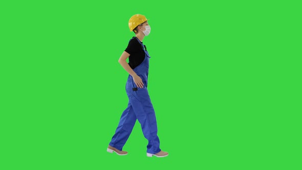 Young Woman in Hard Hat and Medical Mask Walking on a Green Screen, Chroma Key alt