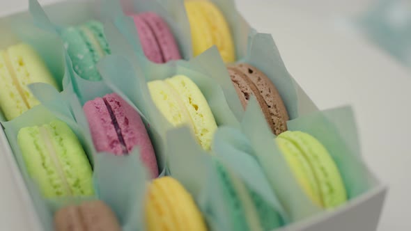 Gift box of color macaron cookies rotating. Close up, slow motion. alt