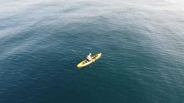 Fisherman trolling in kayak at mediterranean sea aerial drone view in middle of ocean. alt