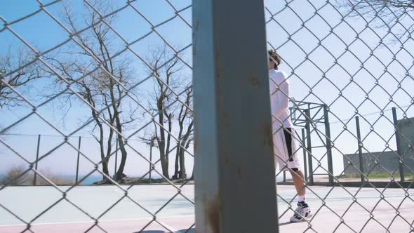 Portrait of a Basketball Player Walking on an Outdoor Basketball Court and Dribbling the Ball Slow alt