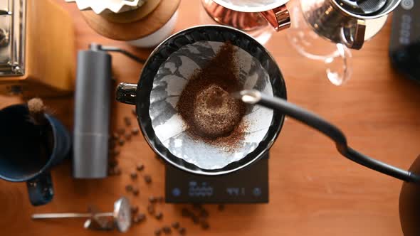 The barista is brewing coffee with traditional drip brewing equipment. alt