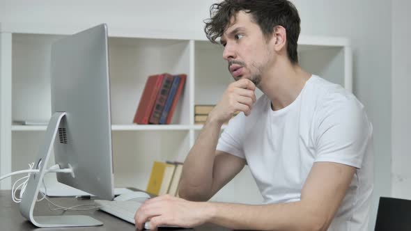 Pensive Creative Man Thinking and Working on Desktop alt